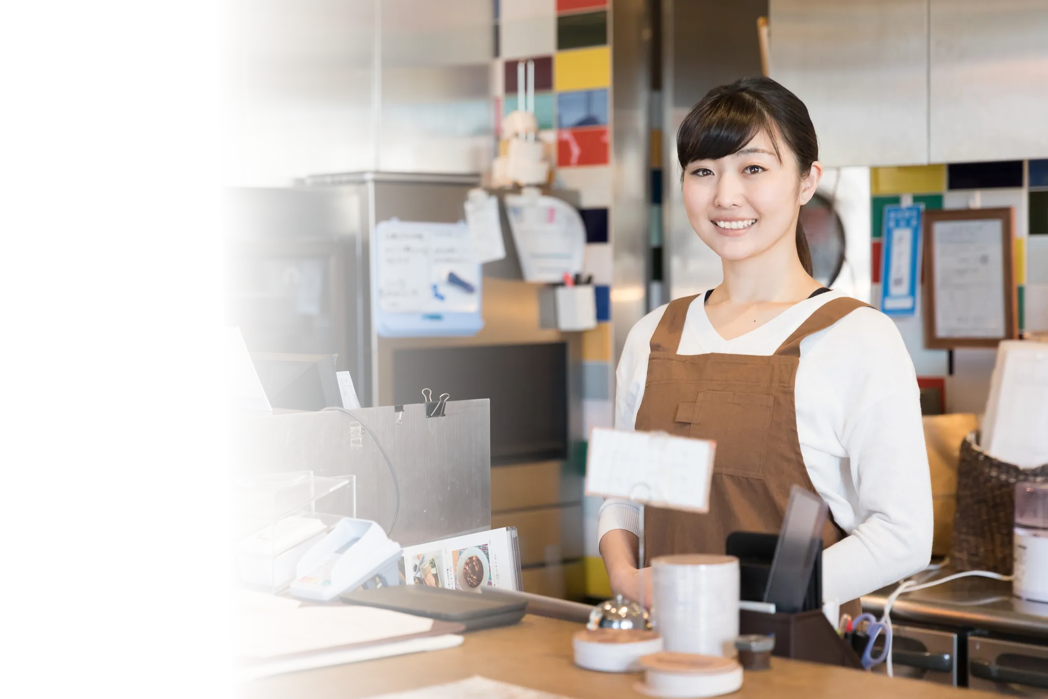 店舗のレジカウンターに立つ、エプロン姿のスタッフ