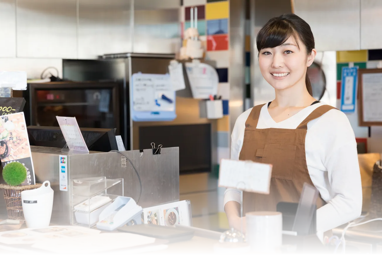店舗のレジカウンターに立つ、エプロン姿のスタッフ